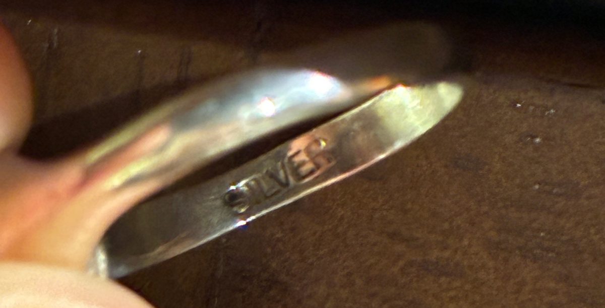 The inside of a silver ring band, stamped with the word SILVER and no number.